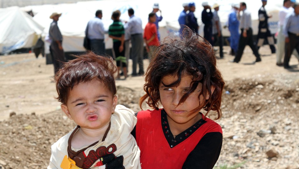 Syrisches Mädchen trägt kleines Kind auf dem Arm.