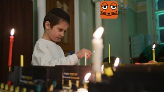Ein Junge mit einer Kippa auf dem Kopf zündet eine Kerze an