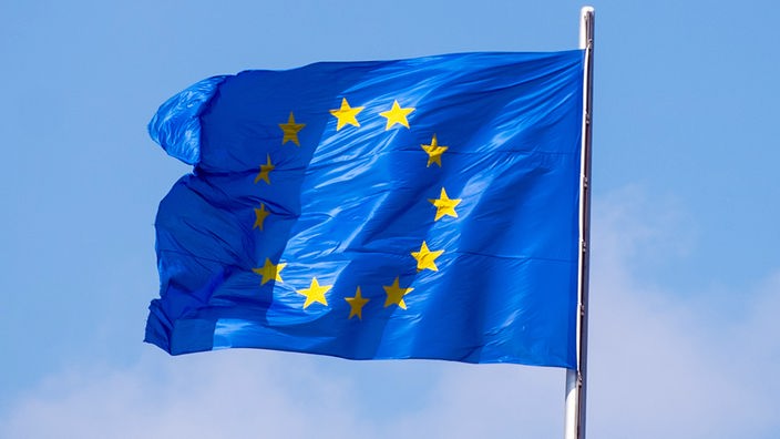 Eine Europaflagge an einem Mast vor blauem Himmel