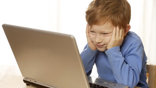 Ein Junge von ca. sechs Jahren sitzt vor einem Laptop.