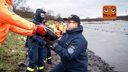 Feuerwehr und Helferinnen und Helfer sichern Deich mit Sandsäcken