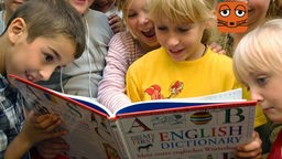Schülerinnen und Schüler gucken in ein englisches Wörterbuch.