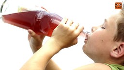 Ein Junge trinkt Saft aus einer Glasflasche