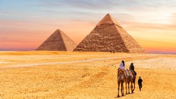 Ägyptische Pyramiden von Giza und Touristen auf Kamelen