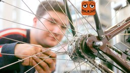 Mann kontrolliert die Radaufhängung eines Fahrrads.