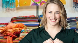 Fotomontage: Auf dem Bild ist eine lächelnde Frau mit blonden Haaren zu sehen, die mit ihren Händen ein Herz formt und vor einem Stand mit bunten Tüchern und dem "Die Maus" Logo des WDR steht.