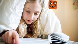 Mädchen liest unter der Bettdecke