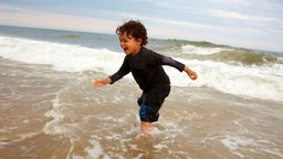 Ein Junge spielt in Meereswellen