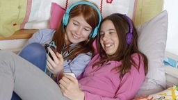 Zwei Mädchen hören gemeinsam Musik.