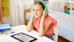 Ein Mädchen hört Musik über grüne Kopfhörer.