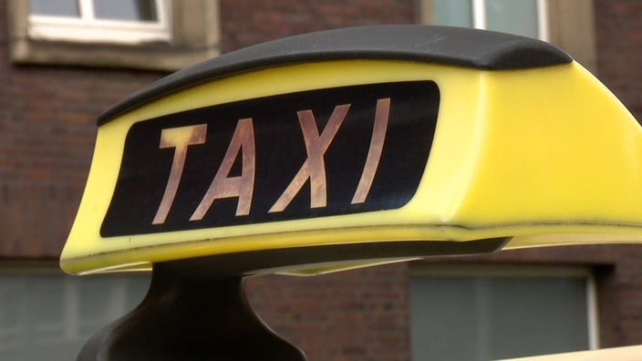 Auf dem Foto ist ein Schild mit der Aufschrift "Taxi", wie es öfter auf Taxis angebracht ist.