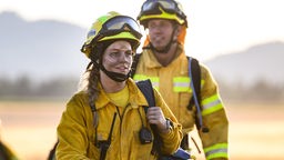 Eine Feuerwehrfrau läuft nach einem Einsatz gegen Waldbrände über eine Wiese