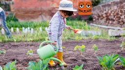 Ein Kind mit einer Gießkanne im Garten