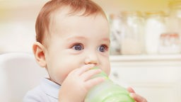 Ein Baby mit blauen Augen trinkt aus einer Trinkflasche