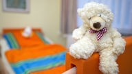 Symbolbild Kinderhospiz, Bett mit Teddybär