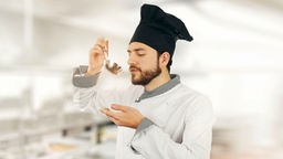 Koch in Restaurantküche probiert von Suppenkelle