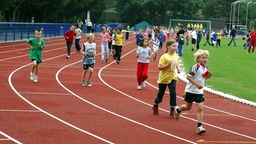 Jungen und Mädchen im Grundschulalter laufen um die Wette.