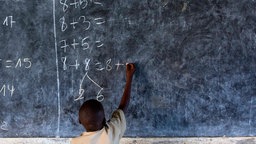 Ein Schüler steht in Burundi an der Tafel und löst Matheaufgaben.