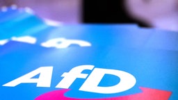 Blaue Fähnchen mit weißem Schriftzug der Partei AfD liegen auf einem Tisch