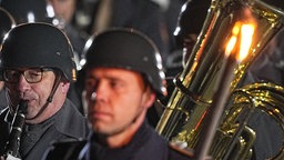Musiker des Musikkorps der Bundeswehr spielen auf der Klarinette und anderen Blasinstrumenten, sie haben Uniformen an und Helme auf