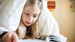 Ein Kind liest ein Buch unter der Bettdecke