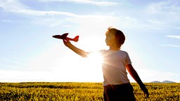 Junge spielt in der Sonne mit einem Spielzeugflugzeug