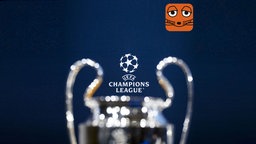 Das Logo der Champions League im Vordergrund, der Pokal unscharf im Hintergrund