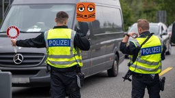 Ein Polizist hält eine Polizeikelle vor einen Lieferwagen. Auf der Polizeikelle steht: Halt, Polizei.