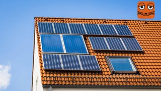 Dunkle Solarpaneele auf einem orangenen Dach schimmern in der Sonne