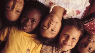 Kinder mit verschiedenen Hautfarben lieben nebeneinander
