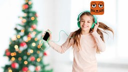 Mädchen mit Musik auf den Ohren tanzt unter dem Weihnachtsbaum