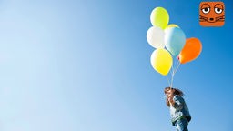 Mädchen hält vor blauem Himmel mehrere bunte Luftballons in der Hand