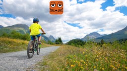 Junge fährt mit dem Fahrrad über einen Schotterweg in bergiger Landschaft