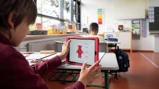 Ein Schüler arbeitet in der Grundschule mit einem Tablet