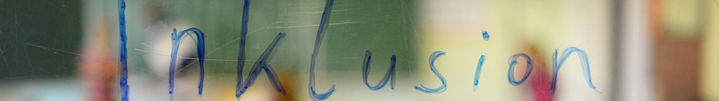 Inklusion in blauer Schrift auf eine Glasscheibe geschrieben.