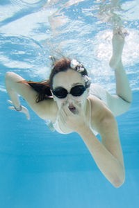 Surfcamp- Mädchen taucht im Schwimmbecken und hält sich die Nase zu
