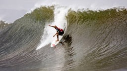 Surfcamp- Surfer sürft in grüner Welle