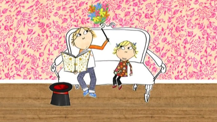 Charlie sitzt auf der Couch und macht Zaubertricks, und Lola schaut ihm dabei zu