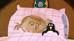 Carola liegt im Bett mit einem Pinguin-Stofftier