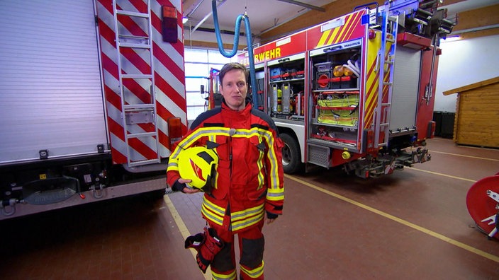 Johannes in Feuerwehr-Uniform mit Helm unter dem Arm