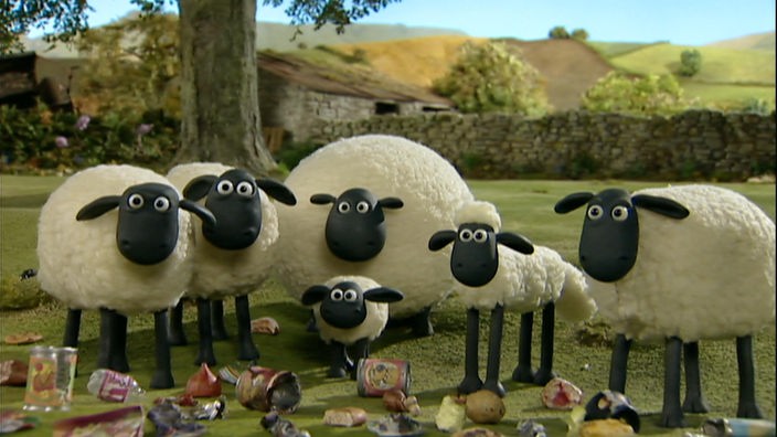 Shaun und die anderen Schafe stehen auf einer Wiese und schauen