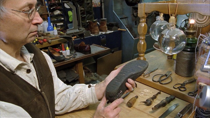 Ein Schuster hält einen Schuh in der Hand