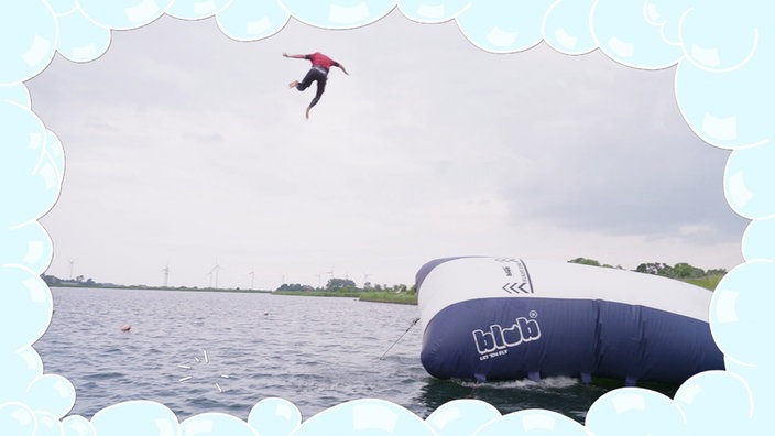 Ein riesiges Luftkissen liegt im Wasser, auf dem steht das Wort "Blob" und André, der in der Luft fliegt 