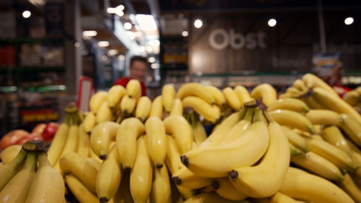 André hinter vielen Bananen im Supermarkt