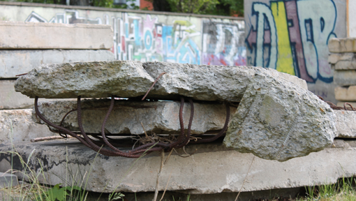 Reste von Betonmauer mit verrosteten Metallstäben liegt auf dem Boden.