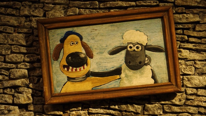 Shaun und Bitzer auf einem Bild mit braunem Rahmen, das an der Wand schief hängt