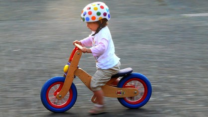 Kind mit Helm auf Laufrad