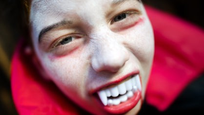 Als Vampir geschminkter Jugendlicher schneidet Grimasse.