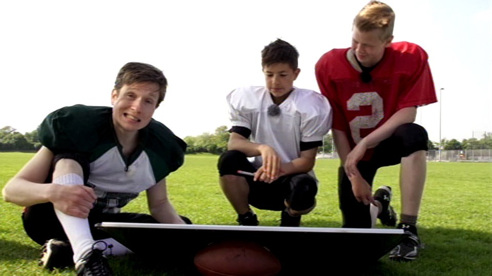 Johannes, Tim und ein weiterer Footballspieler hocken vor einer Tafel.