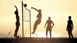 Beachvolleyballspieler bei Sonnenuntergang.